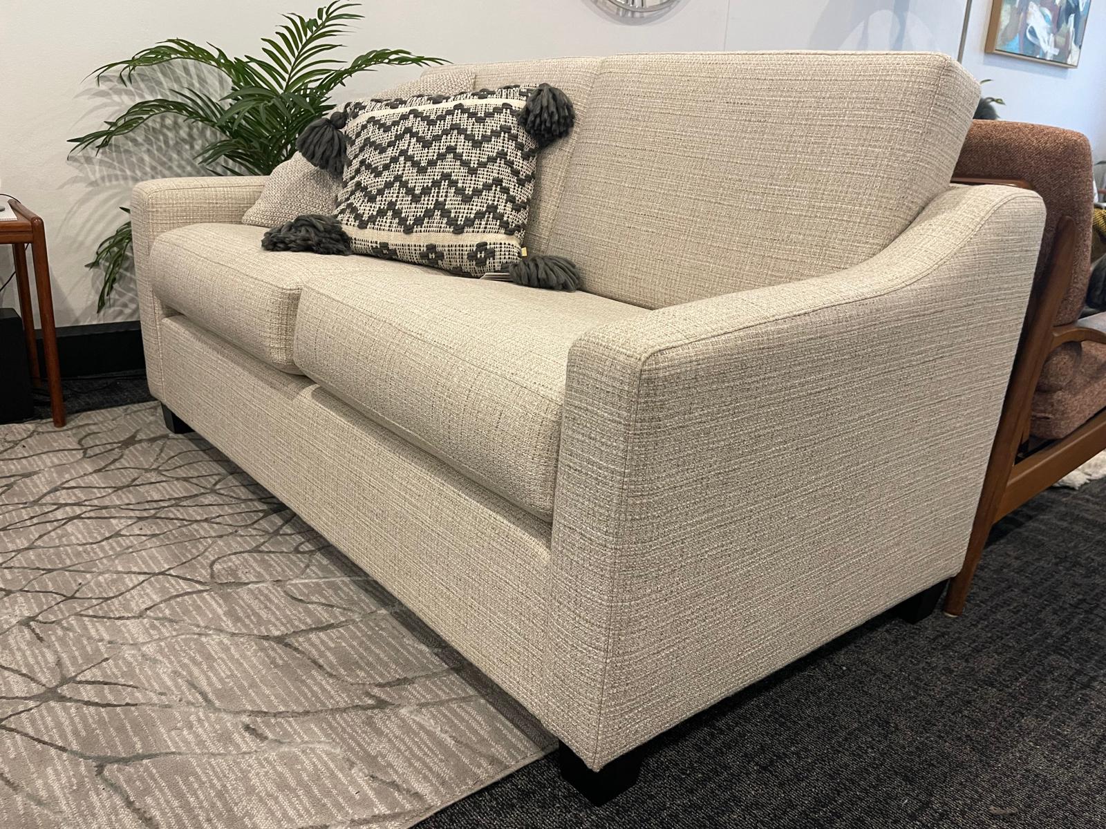 Beige sofa with patterned cushions in a room setting. This is a macquarie lounge by Parker furniture, reupholstered by Covesmore Solutions. Ex Parker People™