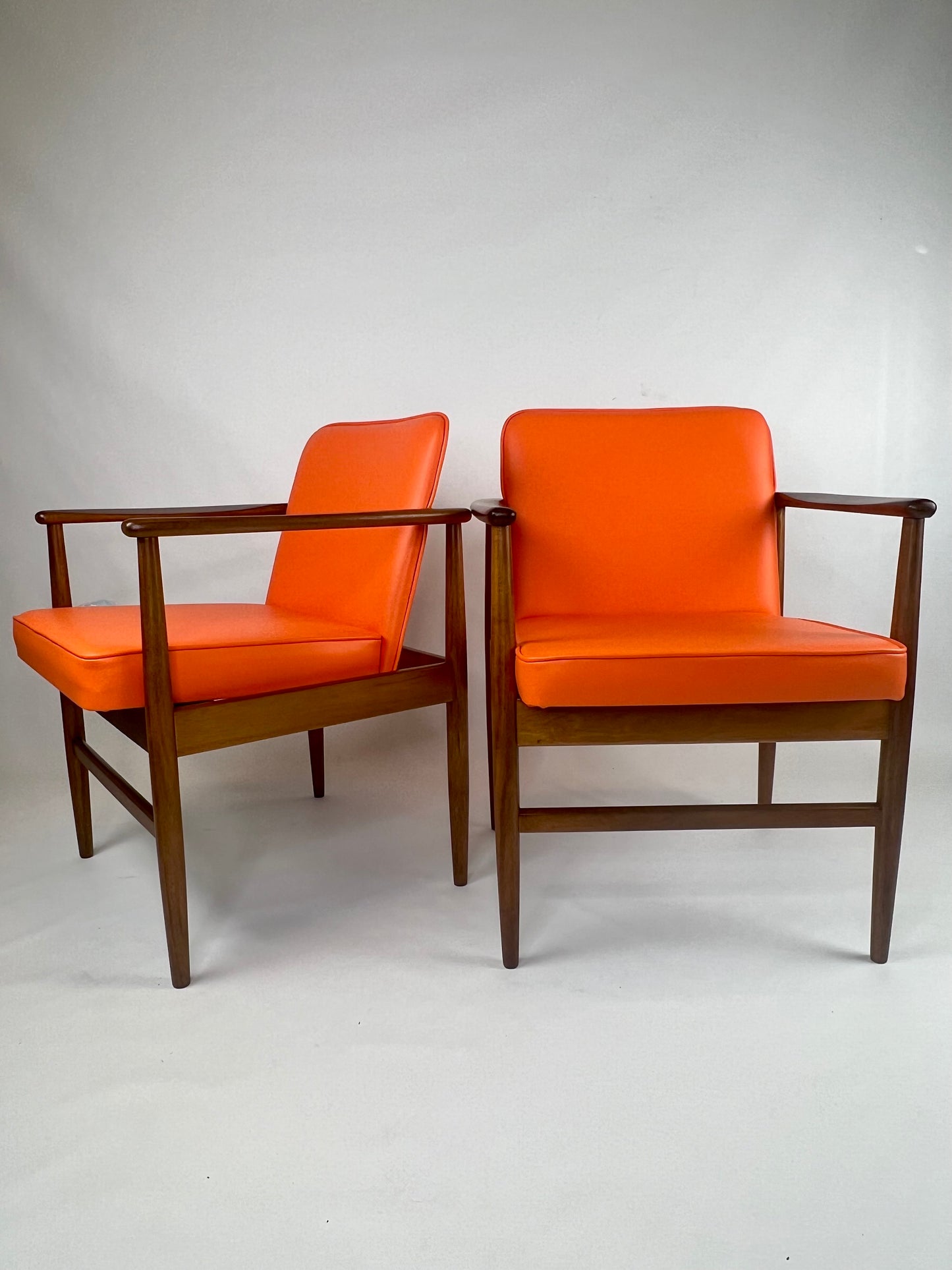 A pair of Arthur Stutchbury chairs, restored and reupholstered in Orange upholstery. These chairs are available for sale in Sydney Showroom.