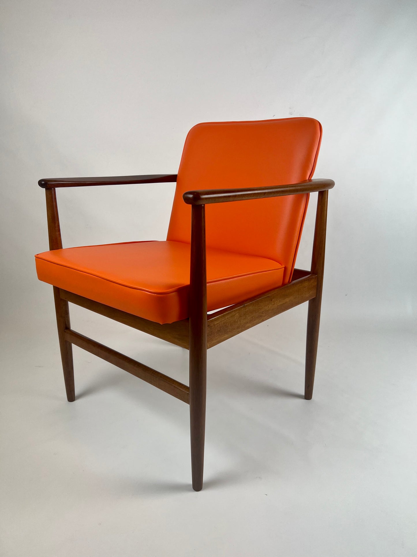 An orange upholstered chair with a wooden frame and armrests. Designed by Arthur Stutchbury, This chair is available for Sale in Willoughby.