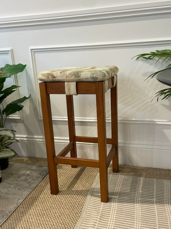 Chiswell bar stool with a cushioned seat against a white wall. Restored by the Ex Parker People™ & available for sale.