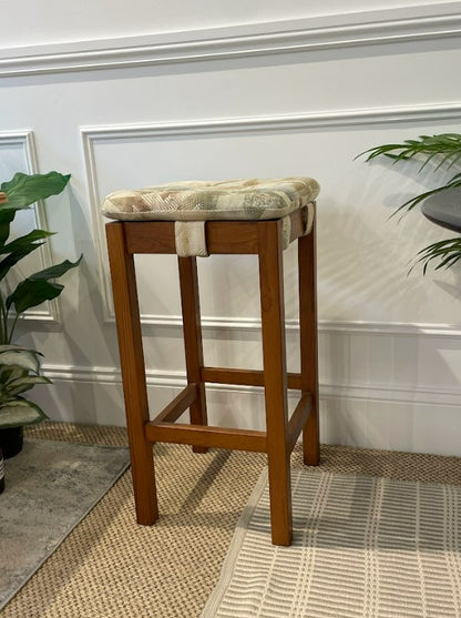 Chiswell bar stool with a cushioned seat against a white wall. Restored by the Ex Parker People™ & available for sale.