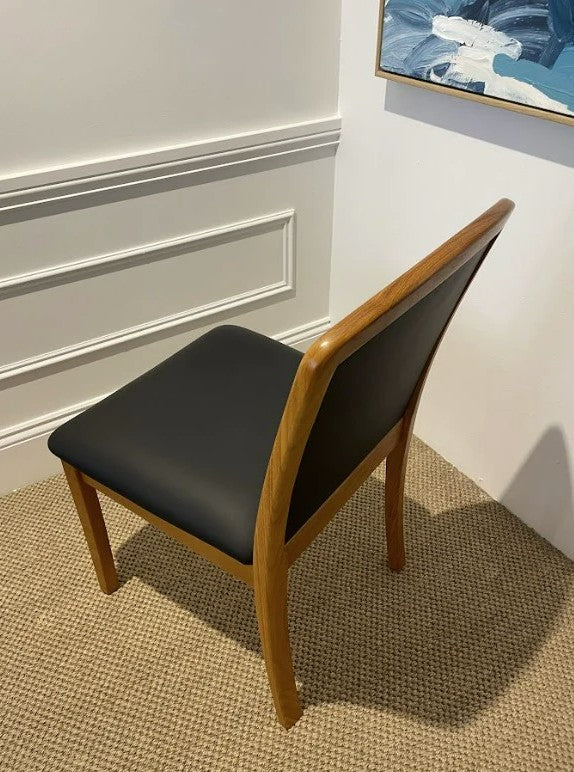 Parker Chair, Model 92 with black leather and wooden frame in a room with a textured wall and abstract painting. Available online or in Willoughby at Parker furniture showroom.