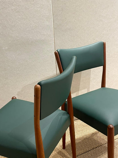 Two Parker 97 Chairs with green material and wooden frames against a textured wall. Refurbishment by Covesmore.