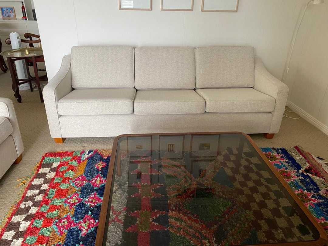 Beige Parker 3-seater sofa in a living room with a colorful rug and glass coffee table. Parker Furniture online by the Ex Parker People™.