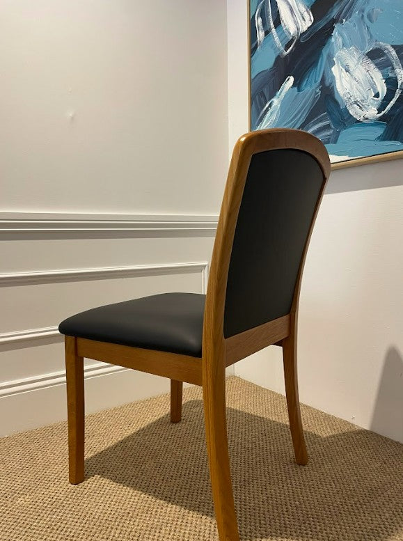 Parker wooden chair with black leather upholstery seat and backrest against a white wall with abstract blue art. Fully restored by Parker furniture experts, Covesmore solutions. Available online & Parker furniture showroom in NSW.