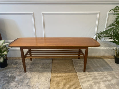 Restored Parker Model 126 teak coffee table with tapered legs and slatted magazine shelf.