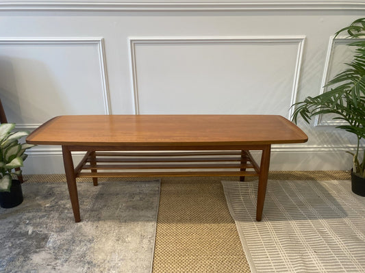 Restored Parker Model 126 teak coffee table with tapered legs and slatted magazine shelf.