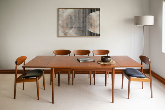 A mid-century modern dining set with a rectangular table and six chairs, featuring a minimalist design with wooden frames, arranged in a bright room with a framed picture on the wall. Ex Parker People™