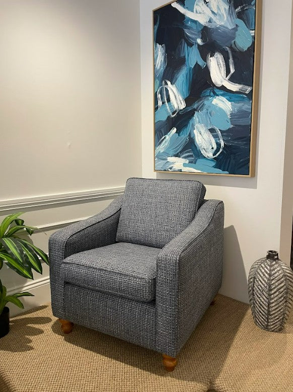A classic armchair in a room with a abstract blue and white painting on the wall. This armchair is part of the Macquarie range by Parker furniture.