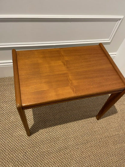 Wooden midcentury table against a white wall with a textured brown carpet. Available online for purchase. Work carried by the Ex Parker People™