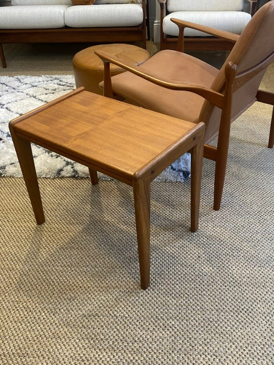 Mid Century side table and chair on a textured floor with a couch in the background. Ex Parker People™