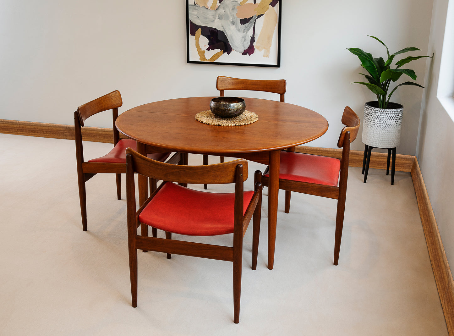 A set of Parker Model 105 dining chairs with red upholstery arranged around a circular wooden extendable Parker dining table, Model  Ex Parker People™