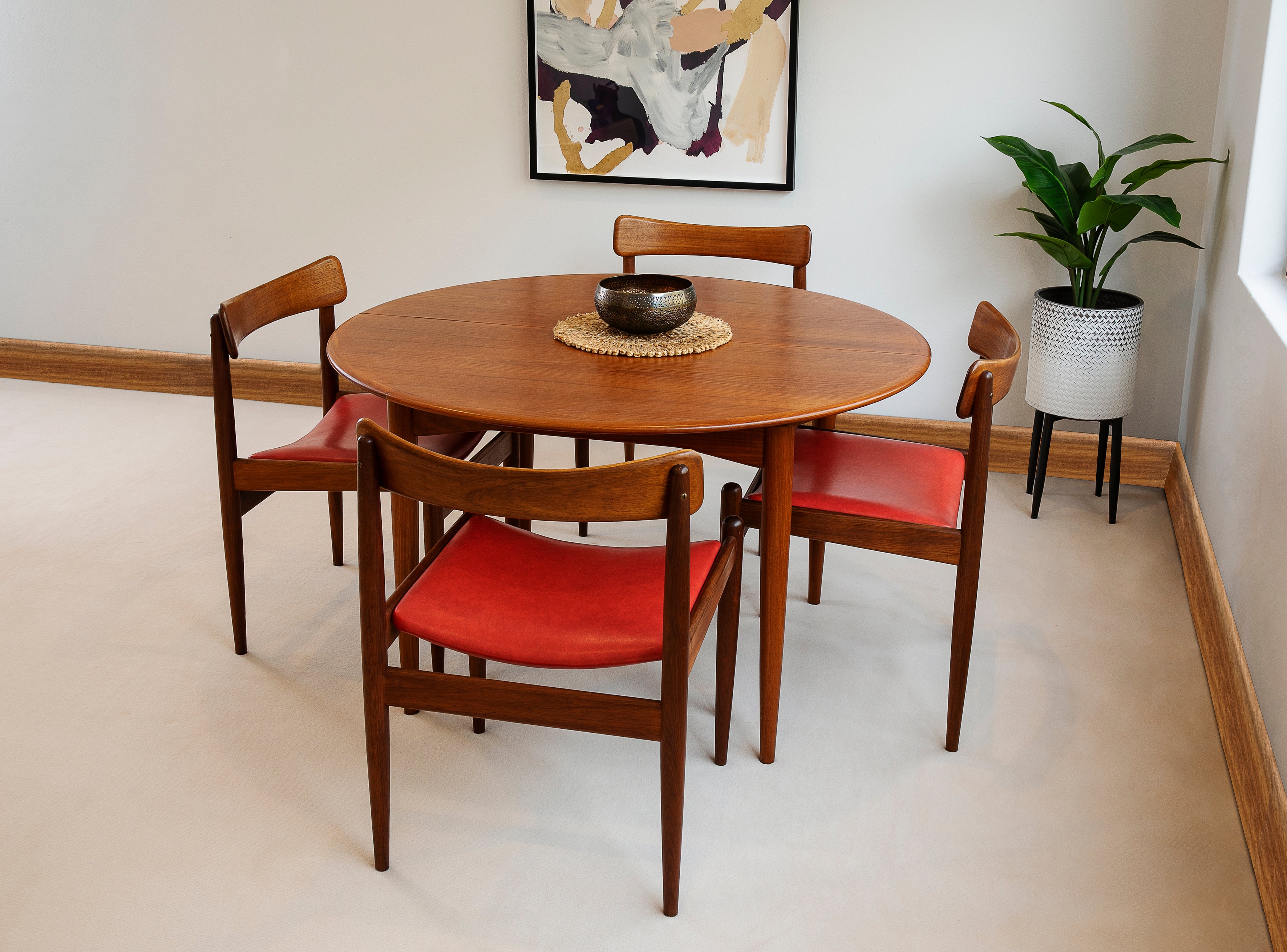 A set of Parker Model 105 dining chairs with red upholstery arranged around a circular wooden extendable Parker dining table, Model  Ex Parker People™